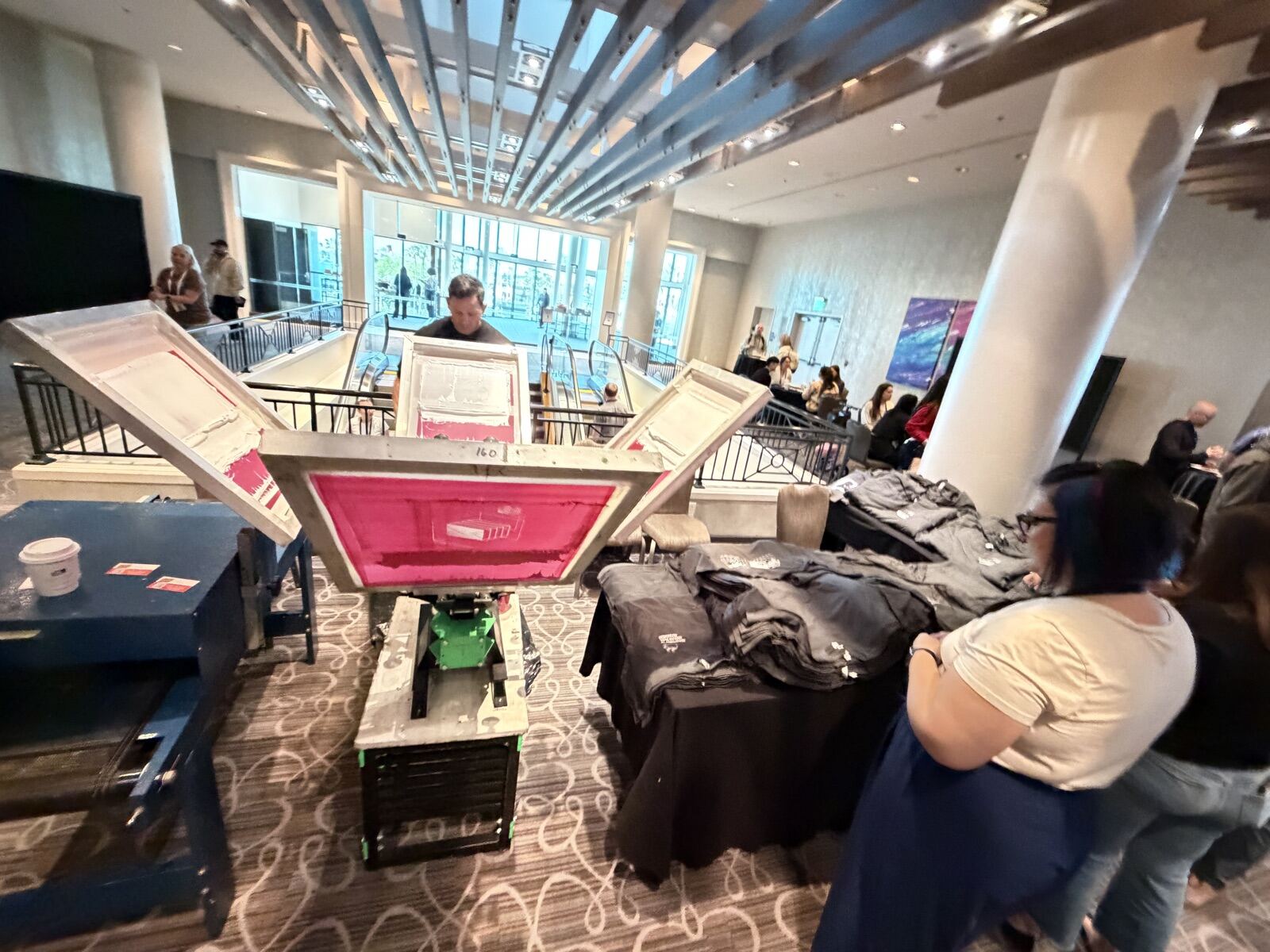 Overhead view of a live printing island in a hotel lobby with apparel spread across tables